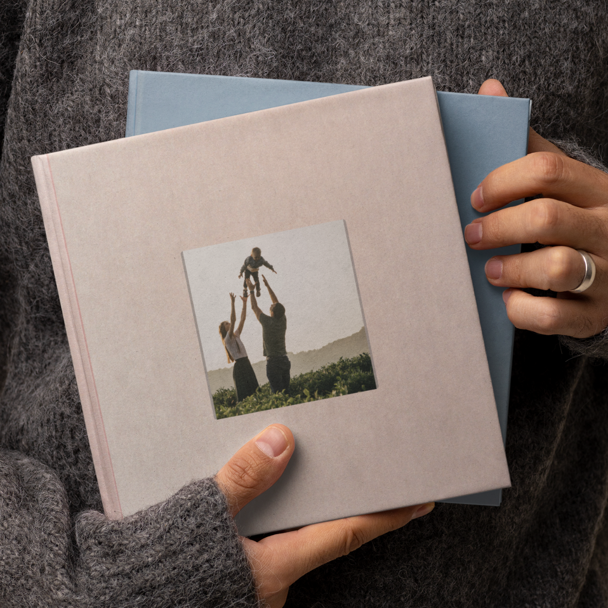 Záběr na osobu držící růžovoou a modrou fotoknihu