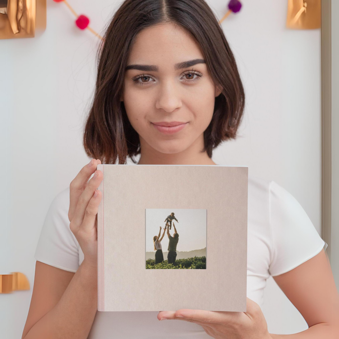 Hnědovlasá slečna držící růžovou fotoknihu s okénkem